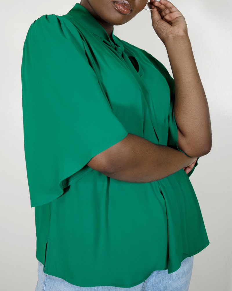 Side of a model wearing a size 28 Bow Blouse with Flutter Sleeve in Green Lake by ELOQUII. | dia_product_style_image_id:290256